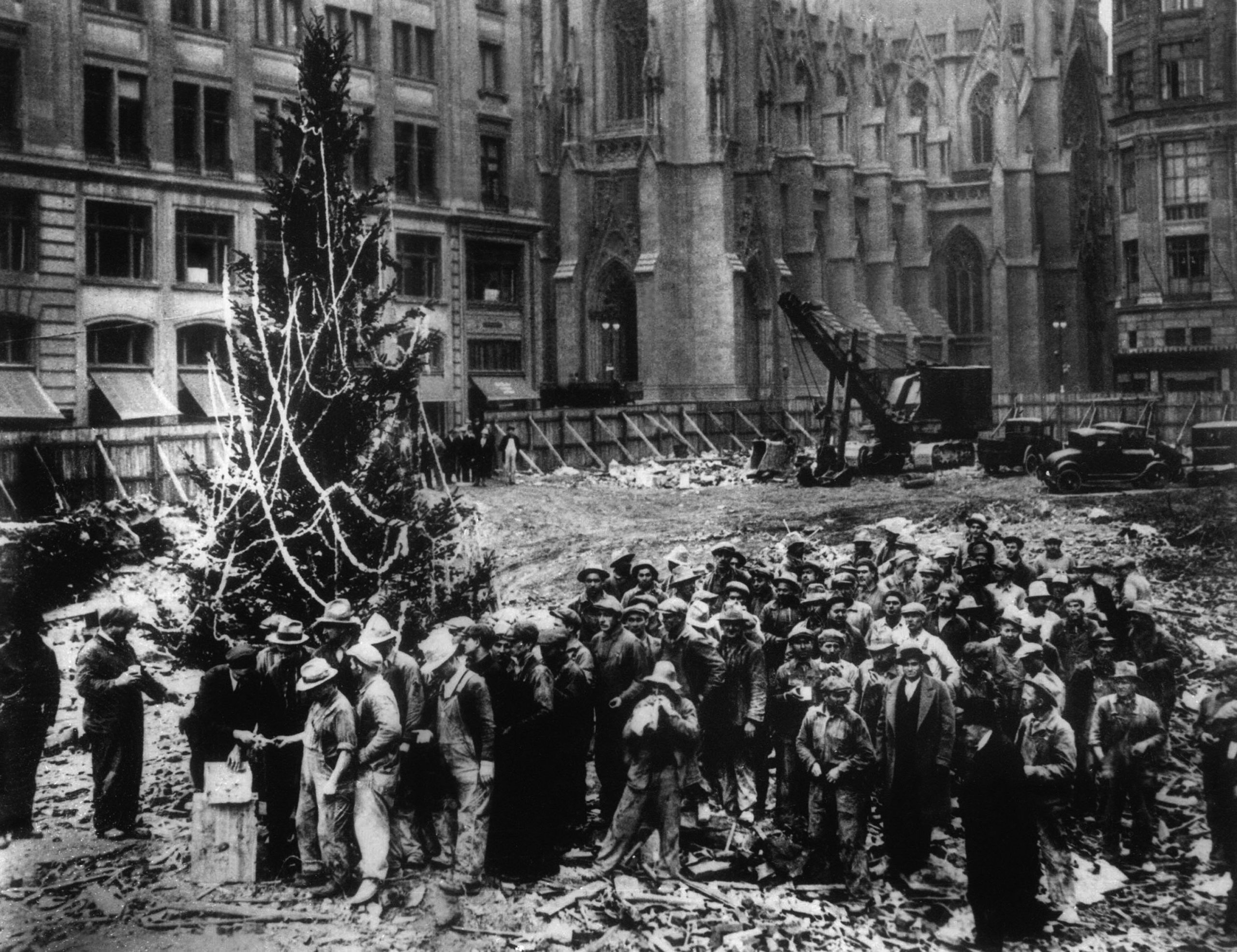 ** FILE ** Construction workers line up for pay beside the first Rockefeller Center Christmas tree in New York in this 1931 file photo. The Christmas tree went on to become an annual tradition and a New York landmark. St. Patrick's Cathedral is visible in the background on Fifth Avenue. 