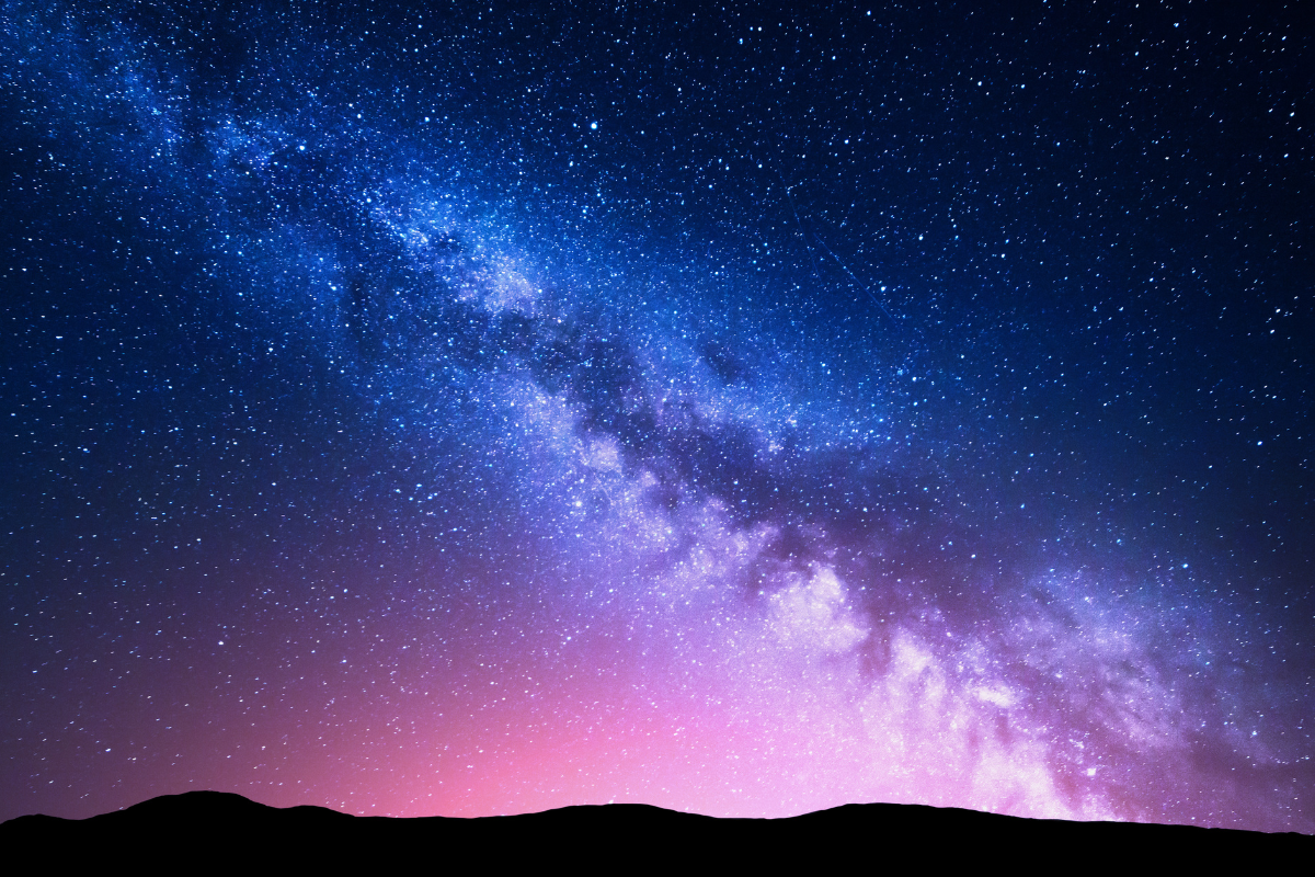 Milky Way and pink light at mountains. Night colorful landscape. Starry sky with hills at summer. Beautiful Universe. Space background with galaxy. Travel background
