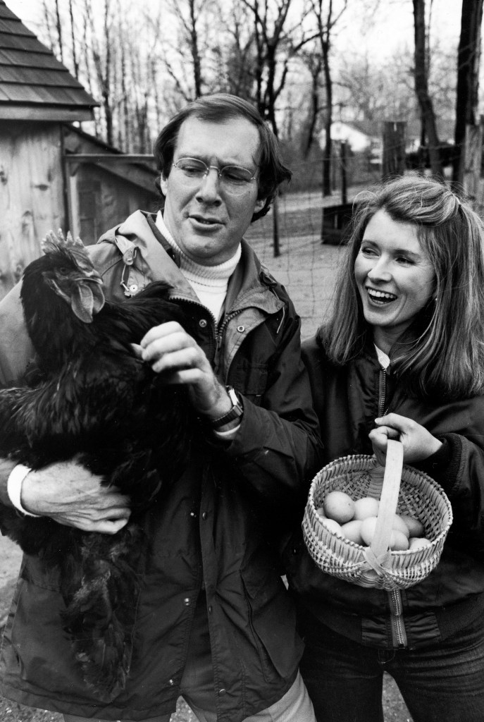 (L-R) Publisher Andy Stewart holding a black Cochin hen and wife, caterer Martha, holding a basket of eggs in barnyard of their home.  