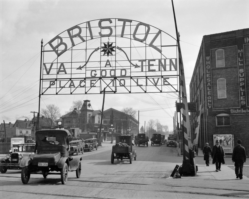1900s 1920s SIGN ON ARCHWAY INDICATING STATE LINE BETWEEN BRISTOL VIRGINIA AND BRISTOL TENNESSEE DOWN MIDDLE OF MAIN STREET 