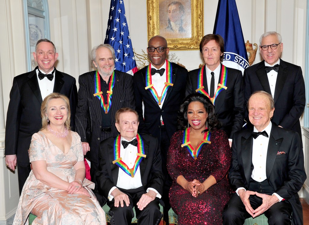 The 2010 Kennedy Center honorees pose for their formal class photo following the formal Artist's Dinner at the United States Department of State in Washington, D.C. on December 4, 2010. Top row, from left to right: Michael M. Kaiser, President, John F. Kennedy Center for the Performing Arts; Merle Haggard; Bill T. Jones; Sir Paul McCartney; and David M. Rubenstein, Chairman, John F. Kennedy Center for the Performing Arts. Bottom row, from left to right: United States Secretary of State Hillary Rodham Clinton; Jerry Herman; Oprah Winfrey; and George Stevens, Jr., creator of "The Kennedy Center Honors". 