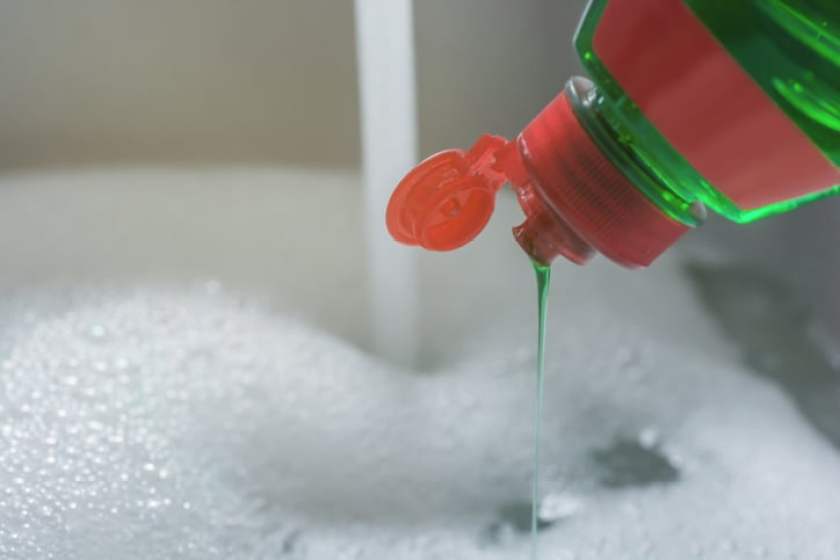 Crockery is washed off in the sink with dishwashing detergent