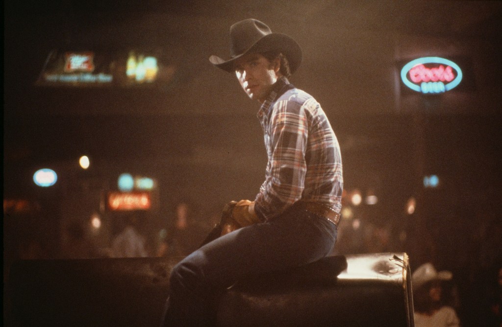 Actor John Travolta rides a mechanical bull in a scene during the Paramount Pictures movie  'Urban Cowboy" circa 1980.