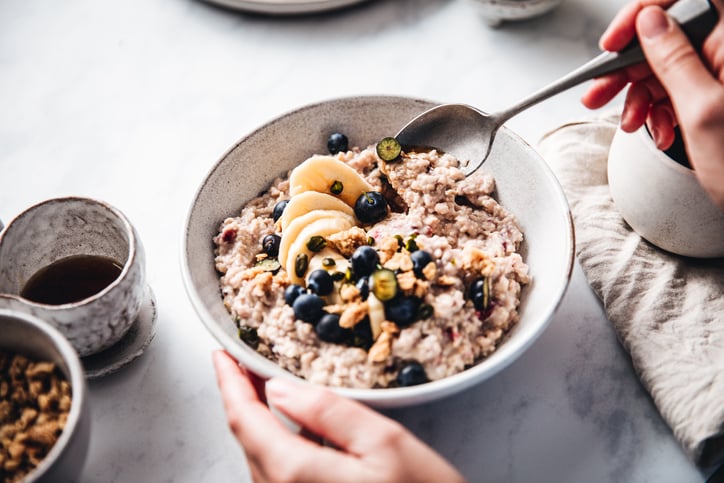  woman mixing oats flour, banana and blueberries in a bowl.