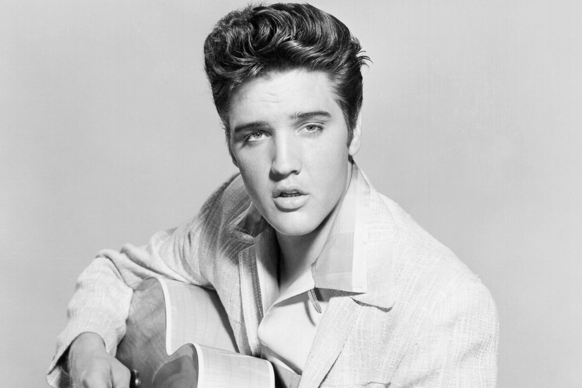 Rock and roll singer Elvis Presley strums his acoustic guitar in a portrait in 1956.