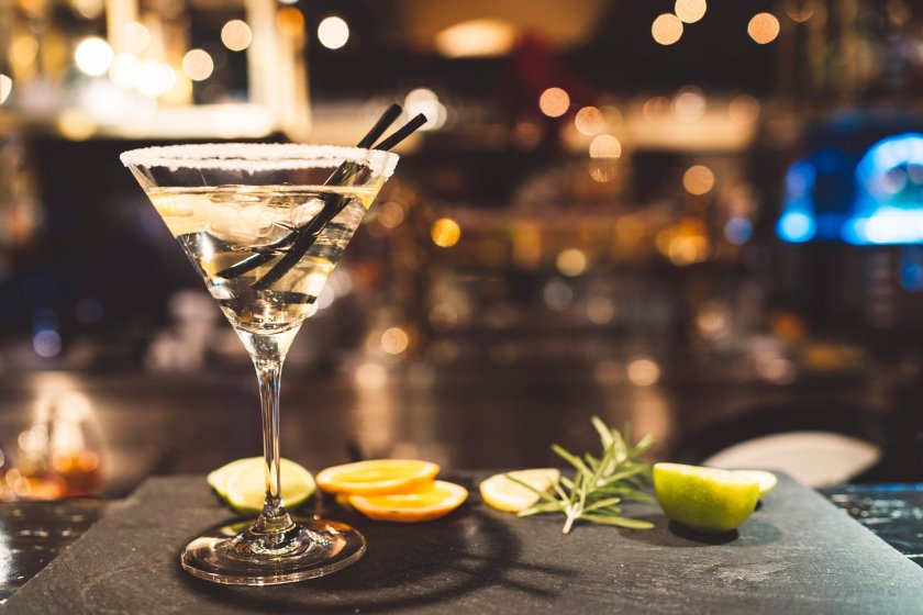 Glass of martini on a grnished surface with lemon slices and rosemary. Black bakground. Glas garnished with sugar on the edge.