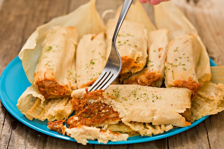 fork is digging in into a chicken tamale.