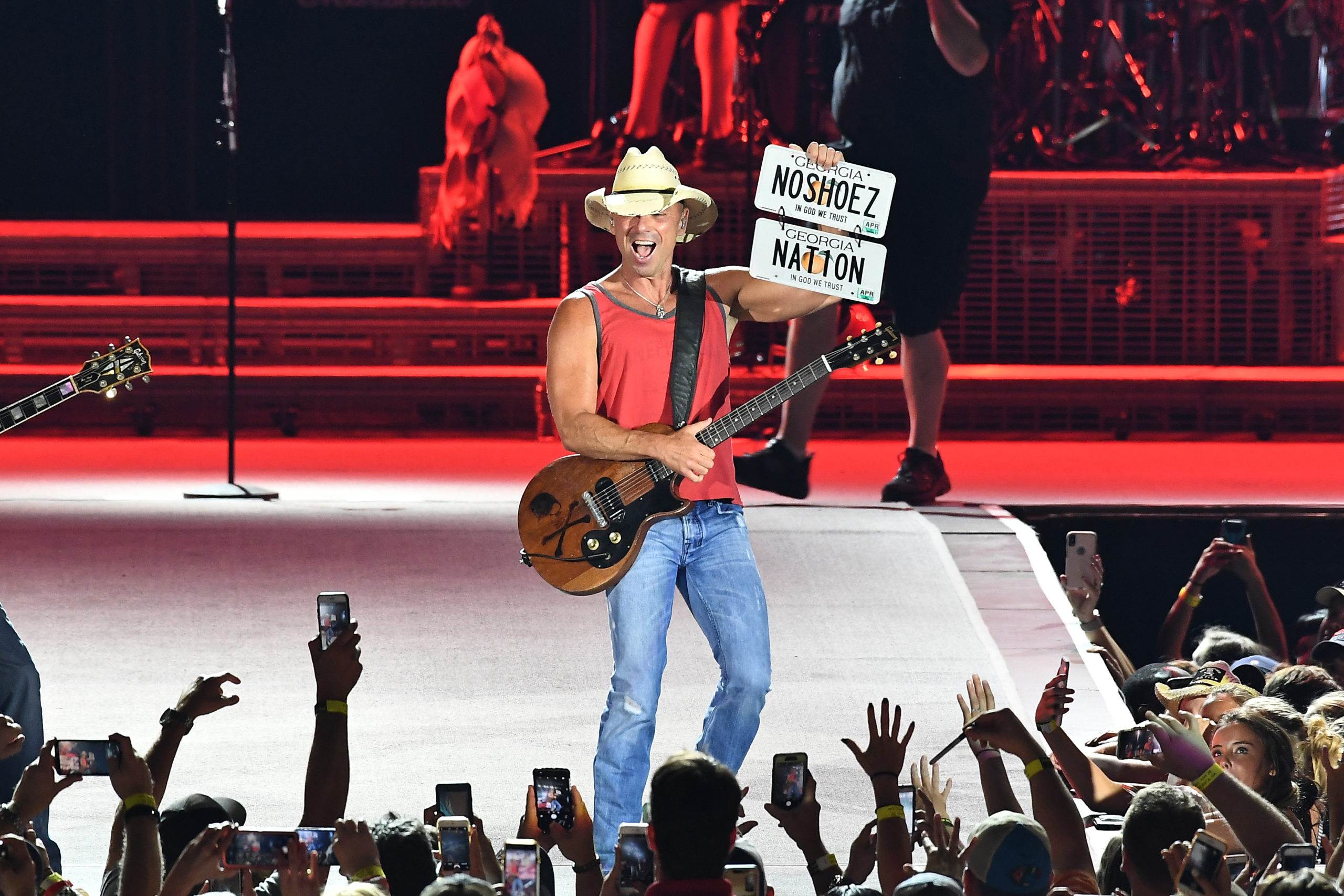 Kenny Chesney hoists a pair of custom Georgia license plates, reading "No Shoez" and "Nat1on"