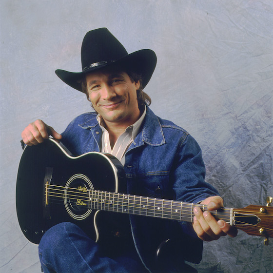 Portrait of American country musician Clint Black as he poses with his guitar, Chicago, Illinois, July 22, 1990.
