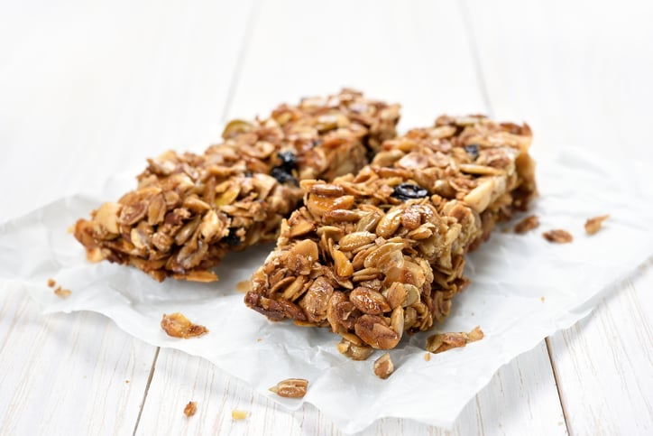 Granola bars on baking paper over white wooden background