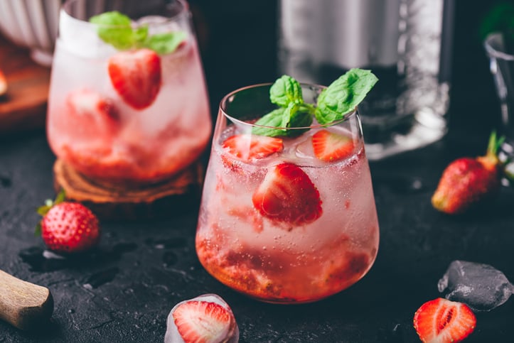 Two glasses of cocktail with fresh and frozen strawberry, gin and tonic