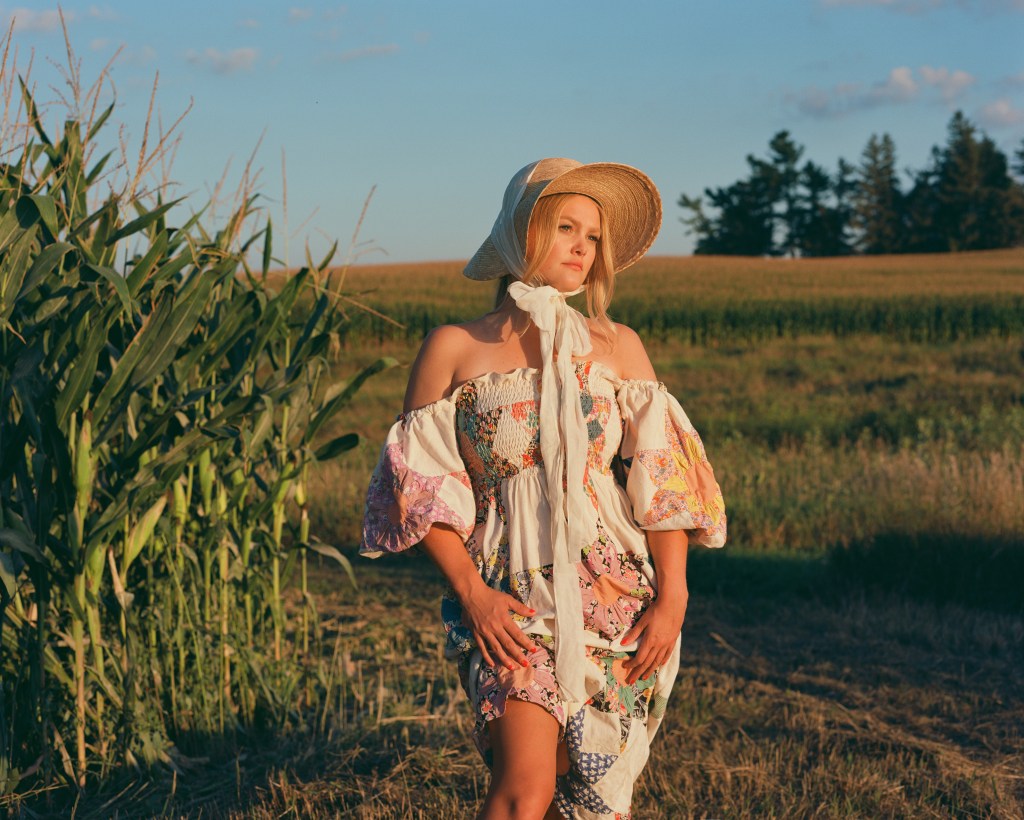 Hailey Whitters stands beside cornfield