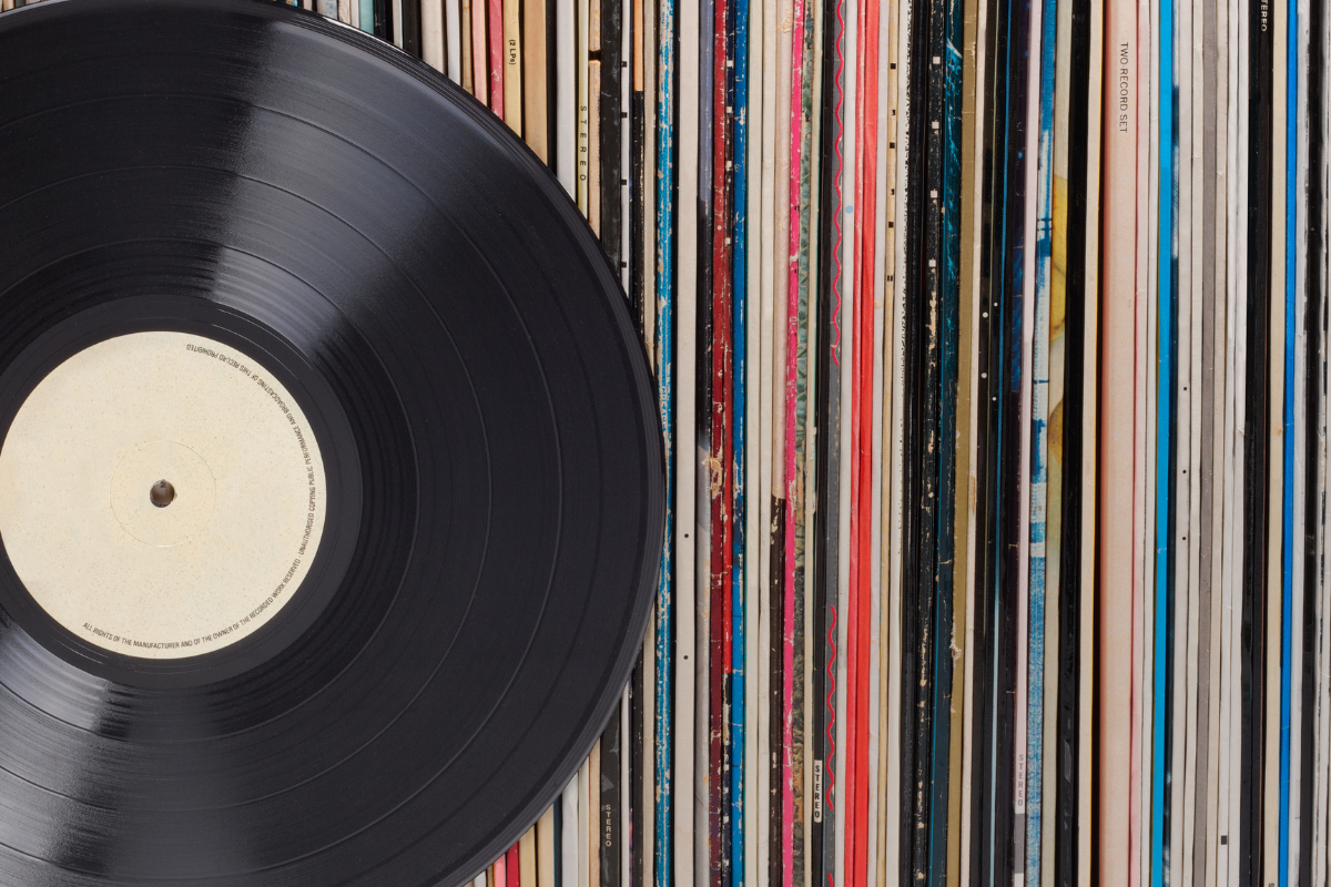 Vinyl records in a row. One record is standing in front. On the record label there is some copy space.