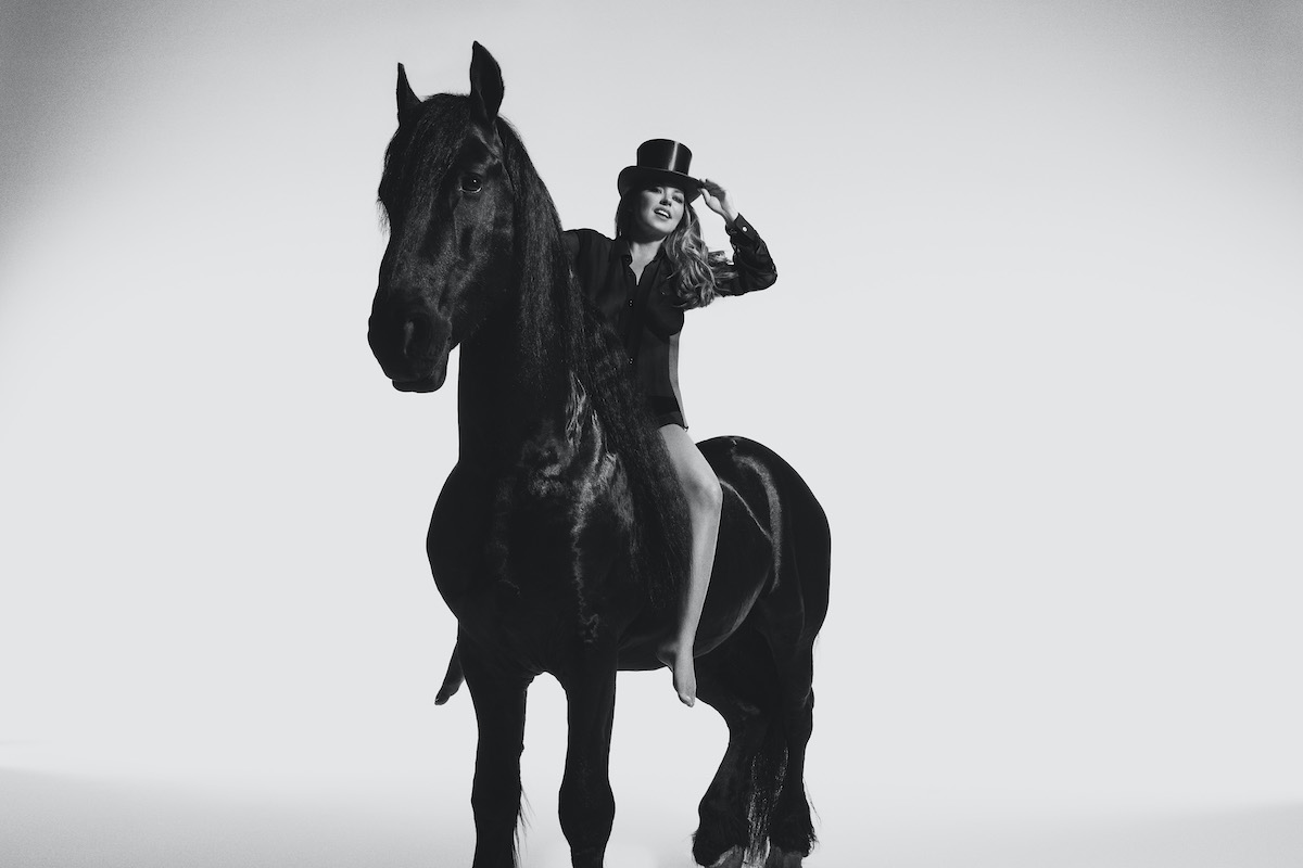 A press shot of Shania Twain for her 2023 album 'Queen of Me.' It shows Twain on a black horse.