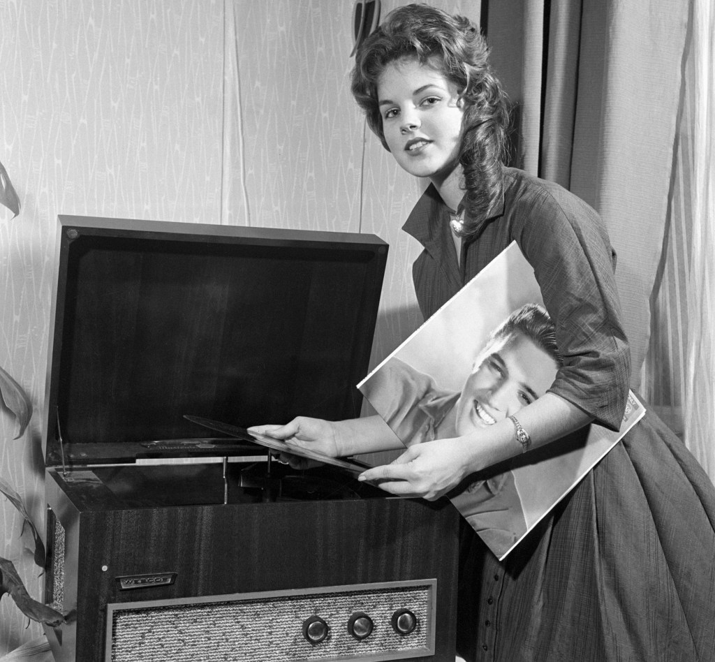 Priscilla Beaulieu, Elvis Presley's "girl back home," plays a record album by the teen idol. Elvis was serving in the US Army in Germany. The couple were married in 1967 and divorced in 1973.