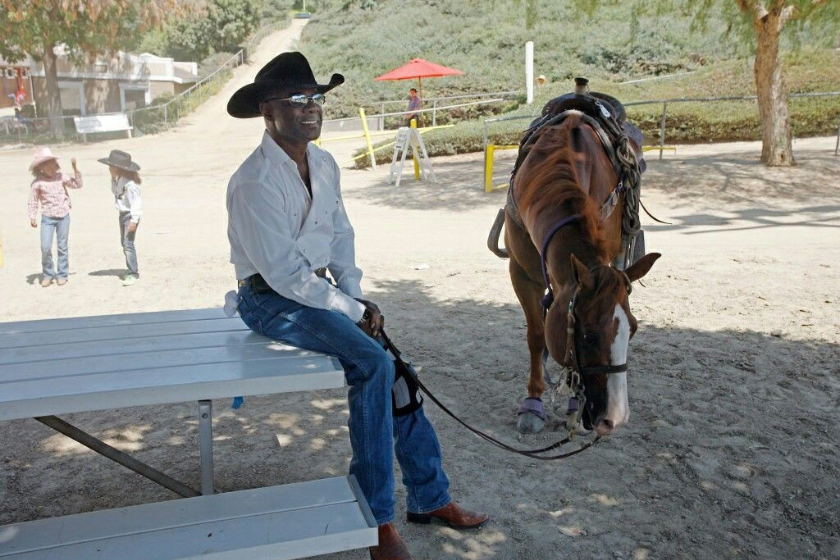 Glynn Turman sits on table next to horse
