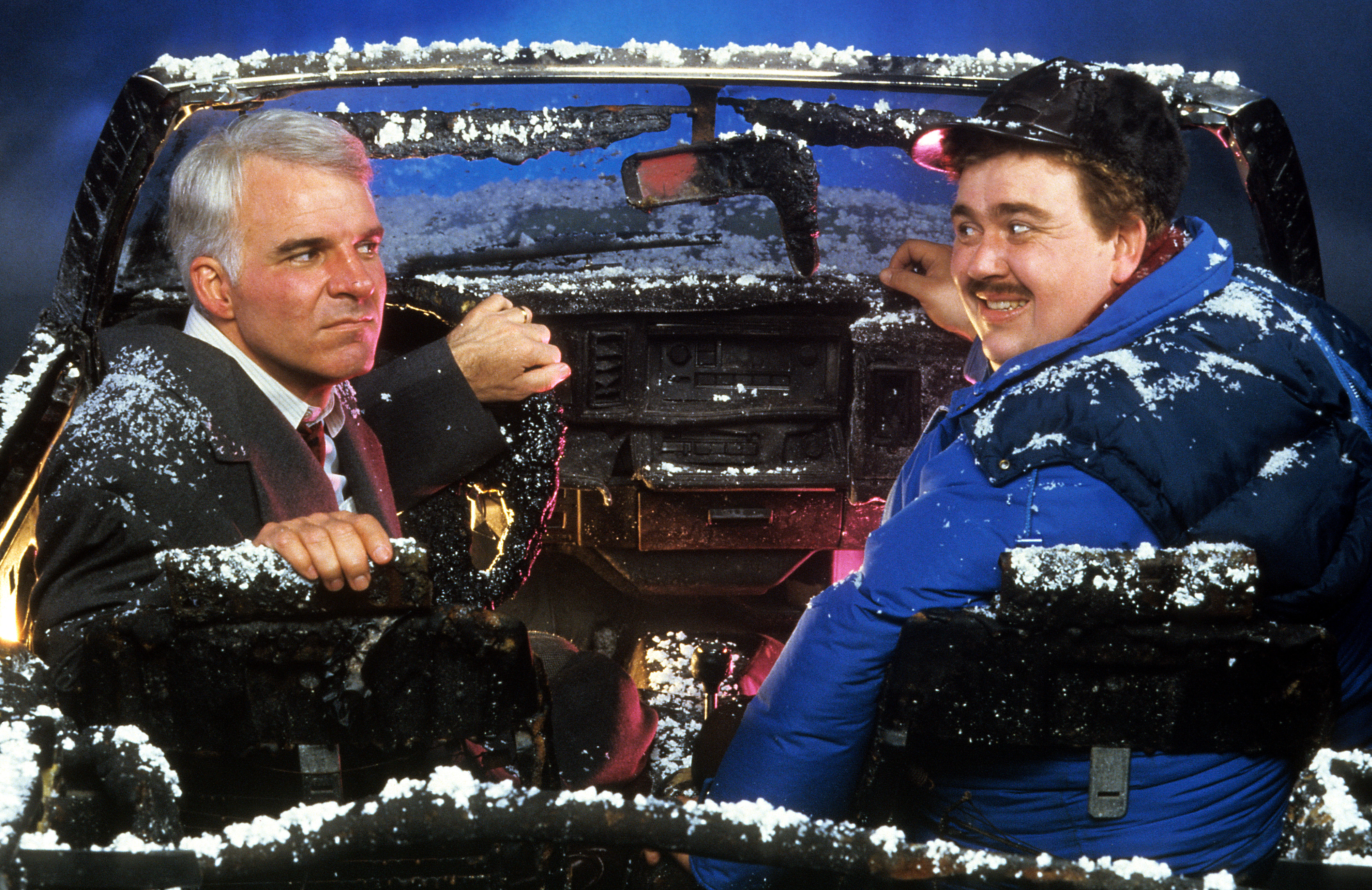 Steve Martin and John Candy sit in a destroyed car in a scene from the film 'Planes, Trains & Automobiles', 1987. 