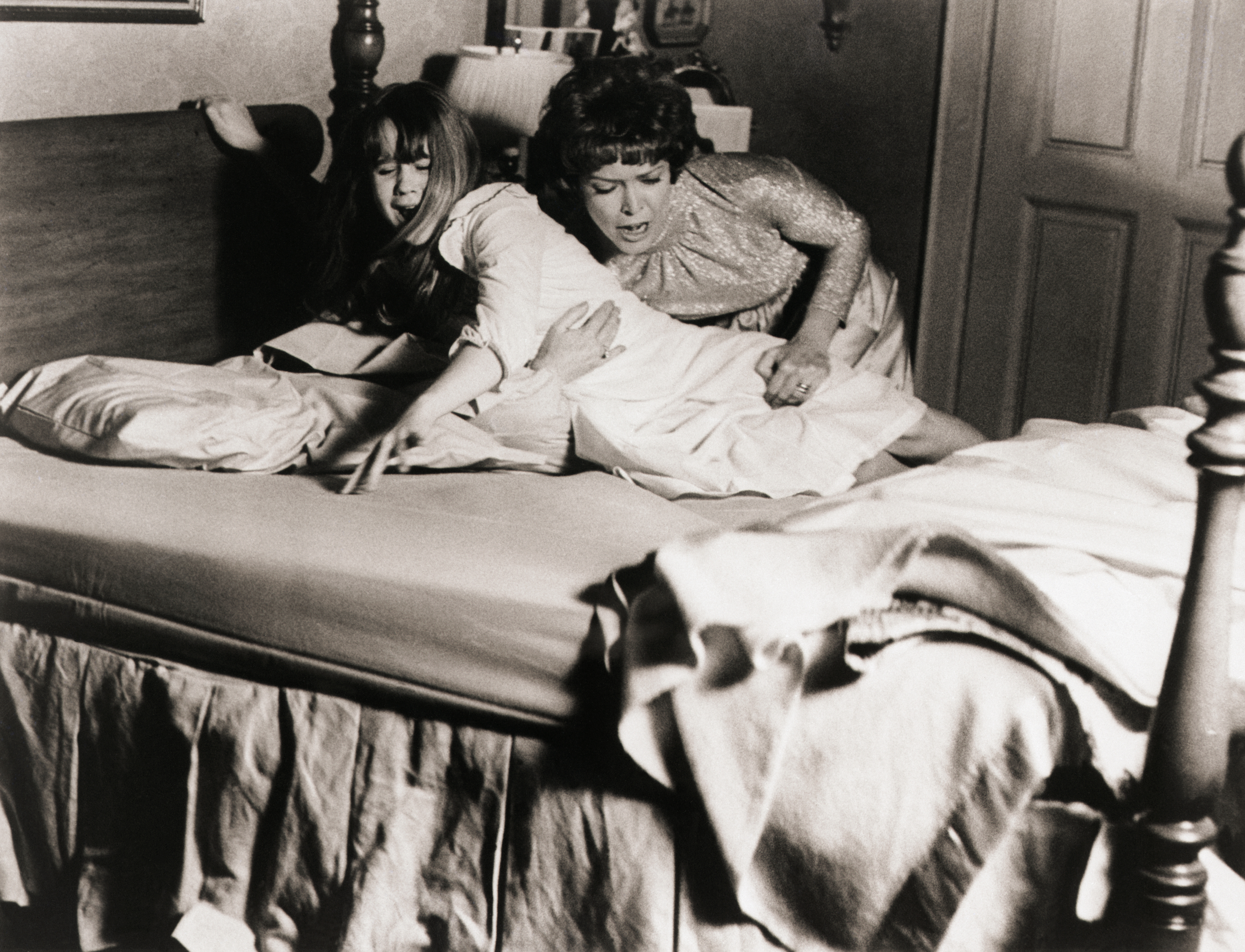 (Original Caption) 1973- Picture shows actress, Ellen Burstyn(R), struggling to keep her daughter, actress Linda Blair(L), in her bed during a scene from the 1973 movie "The Exorcist".