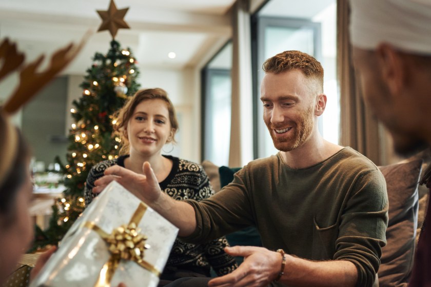 Shot of young friends opening their Christmas gifts together at home
