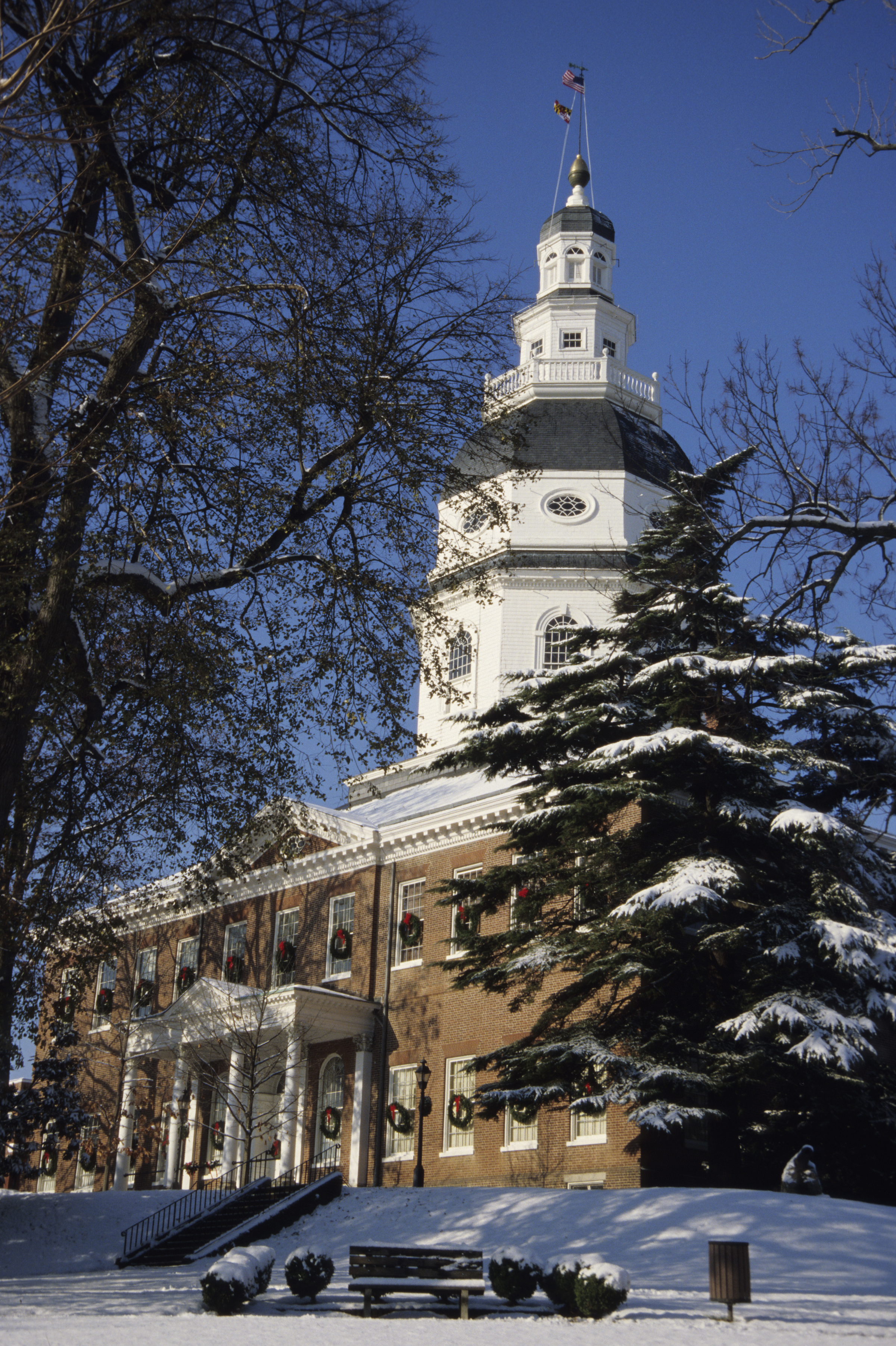 The Maryland Statehouse with snow and holiday wreaths.