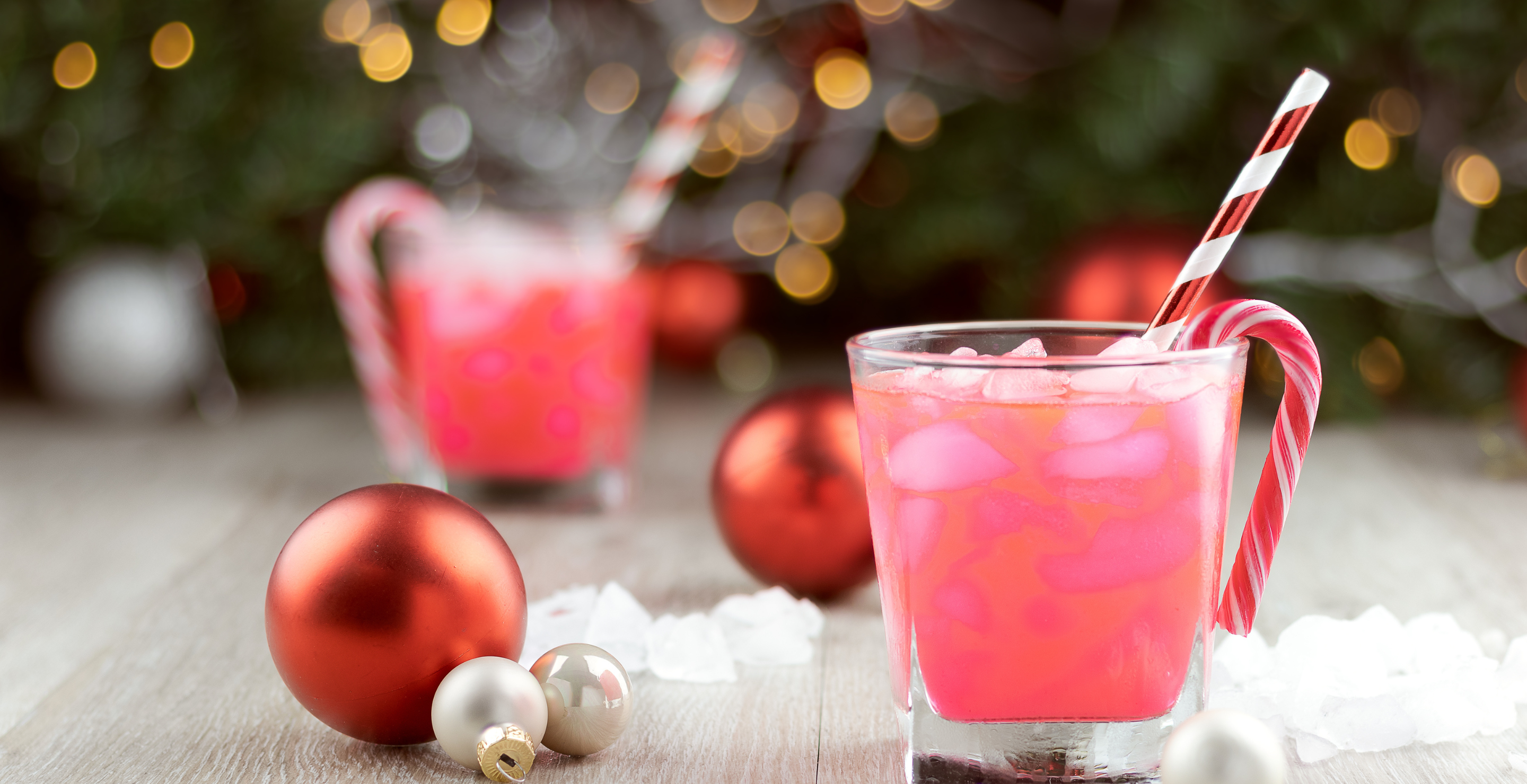 Two christmas party drinks with ice, straws and candy canes and sweets, copy space