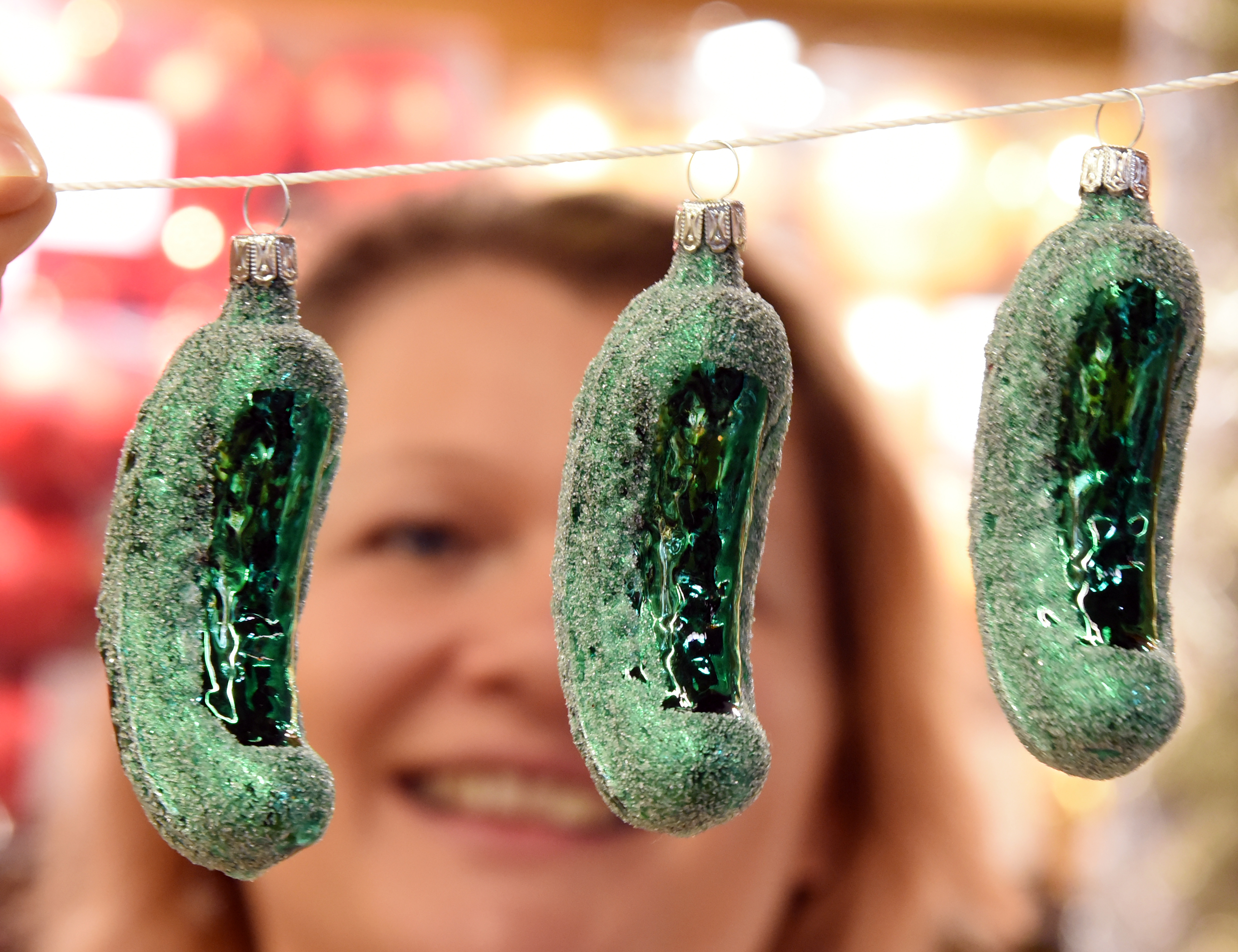 08 November 2022, Saxony-Anhalt, Spickendorf Bei Halle/Saale: Managing director Alexandra H&auml;der holds glass cucumbers as Christmas tree ornaments in her hands in her ceramics barn in Spickendorf near Halle. In the USA, it is a widespread custom to hang the so-called "Christmas Pickle" somewhat hidden in the branches as the last tree ornament. Whoever finds it first receives an extra Christmas present and good luck in the coming year. Already since August, the "Christmas Wonderland" has been set up in their barn on about 800 square meters and is now supplemented with new Christmas decorations. Several thousand Christmas decoration artefacts are intended to get customers in the mood for the festive season. With suggestions for decorating the Christmas parlor and the festive dining table, Alexandra H&auml;der wants to encourage a stress-free and peaceful gathering of the whole family. 