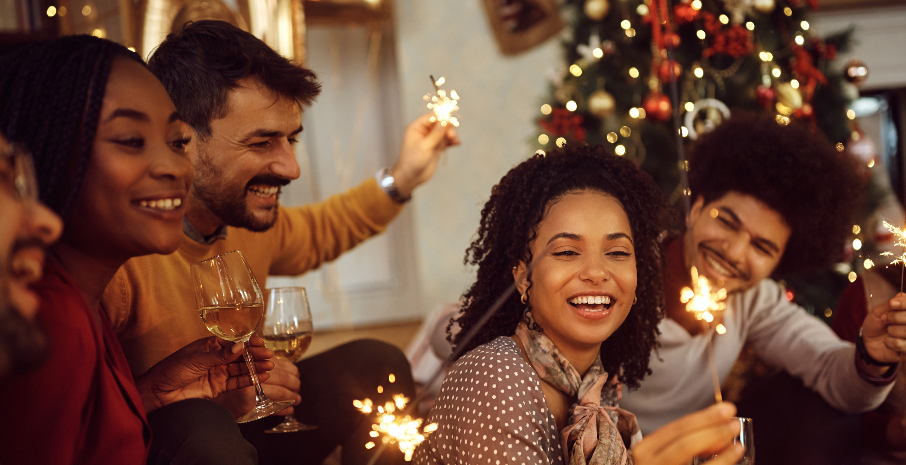 Cheerful friends having fun with sparklers during Christmas party at home.
