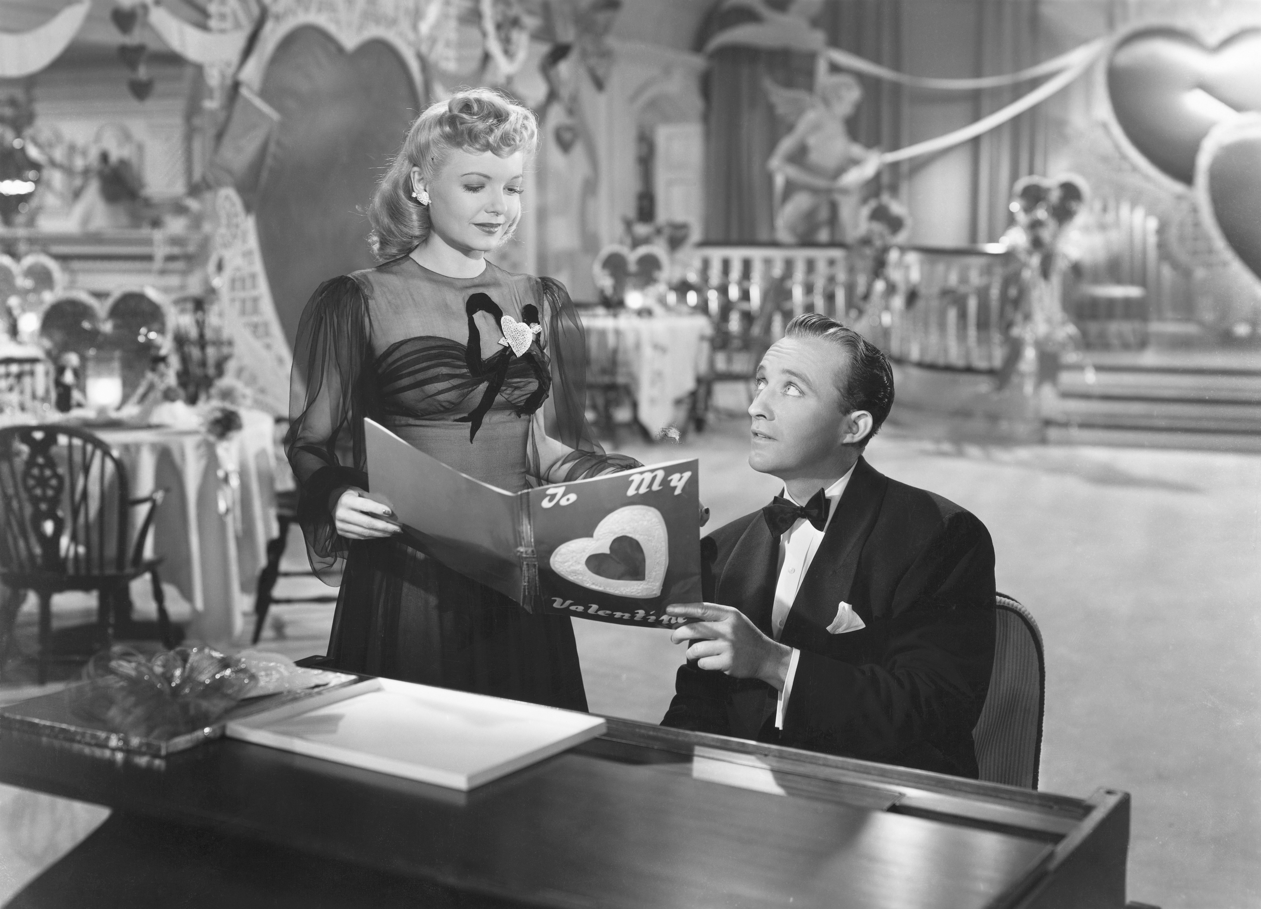 Linda Mason (Marjorie Reynolds) joins Jim Hardy (Bing Crosby) at the piano to look at a Valentine in his nightclub the Holiday Inn in the 1942 musical Holiday Inn. 