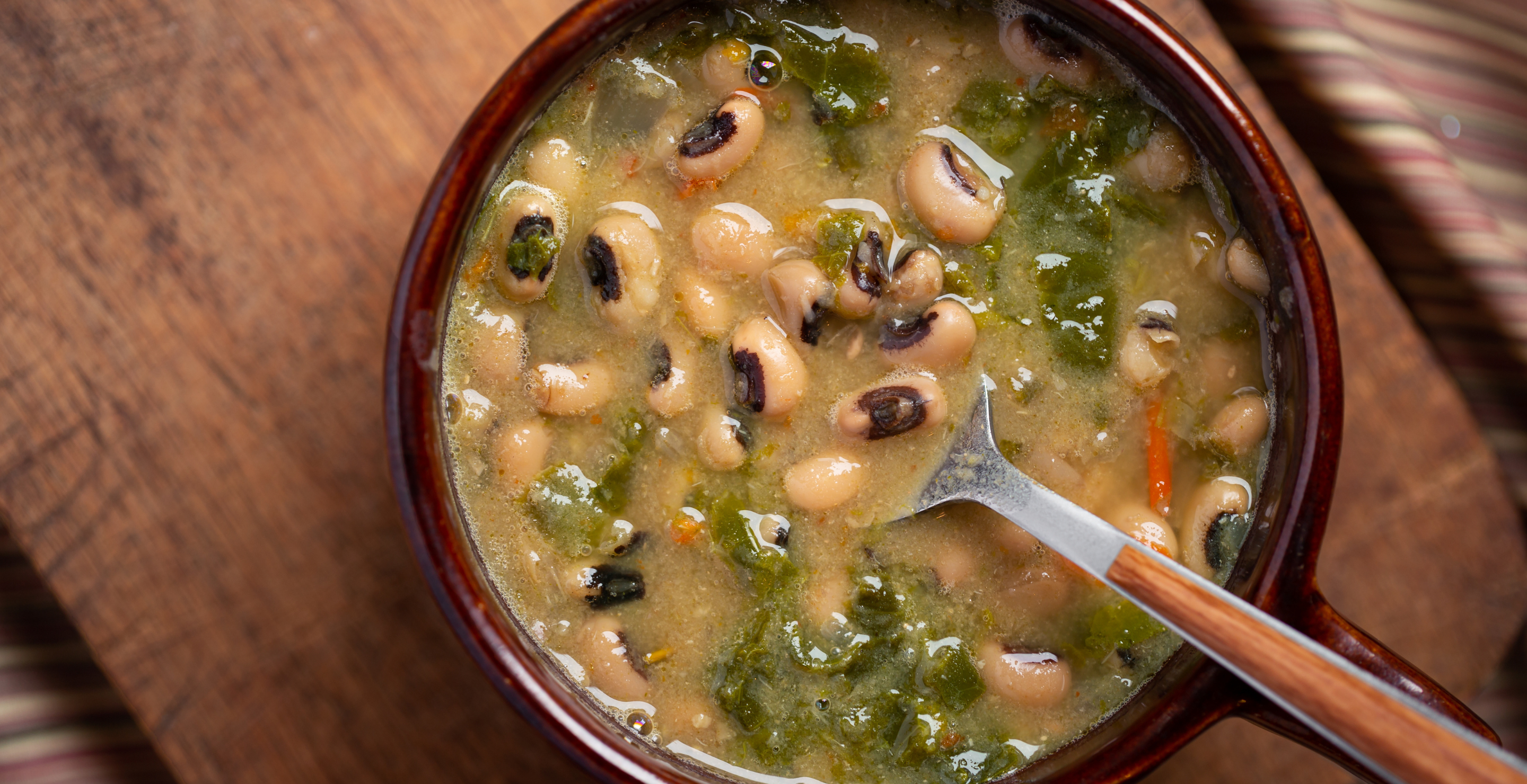 Overhead view of black eyed peas and collard greens in brown bowl
