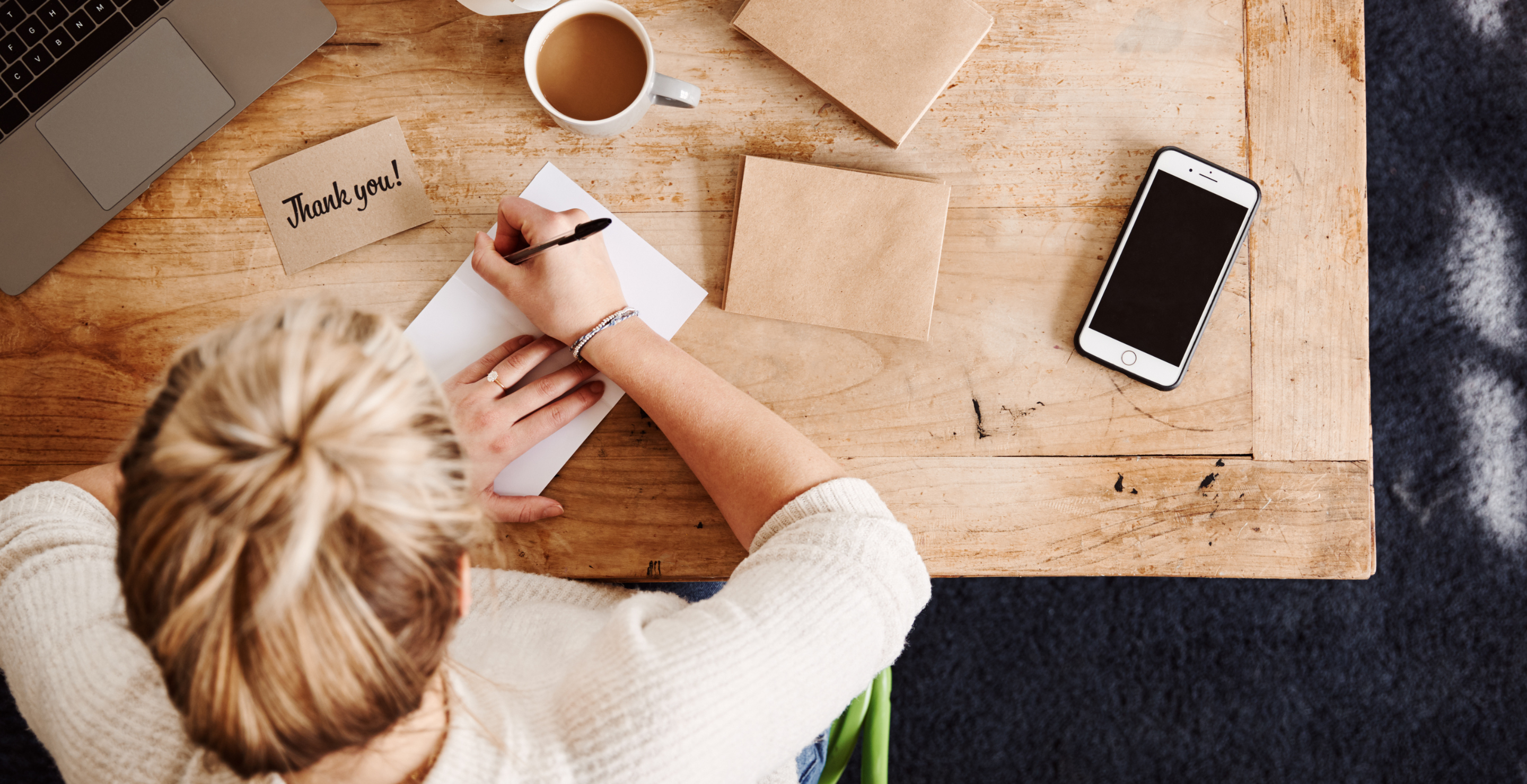 Overhead Shot Looking Down On Woman Writing In Generic Thank You Card