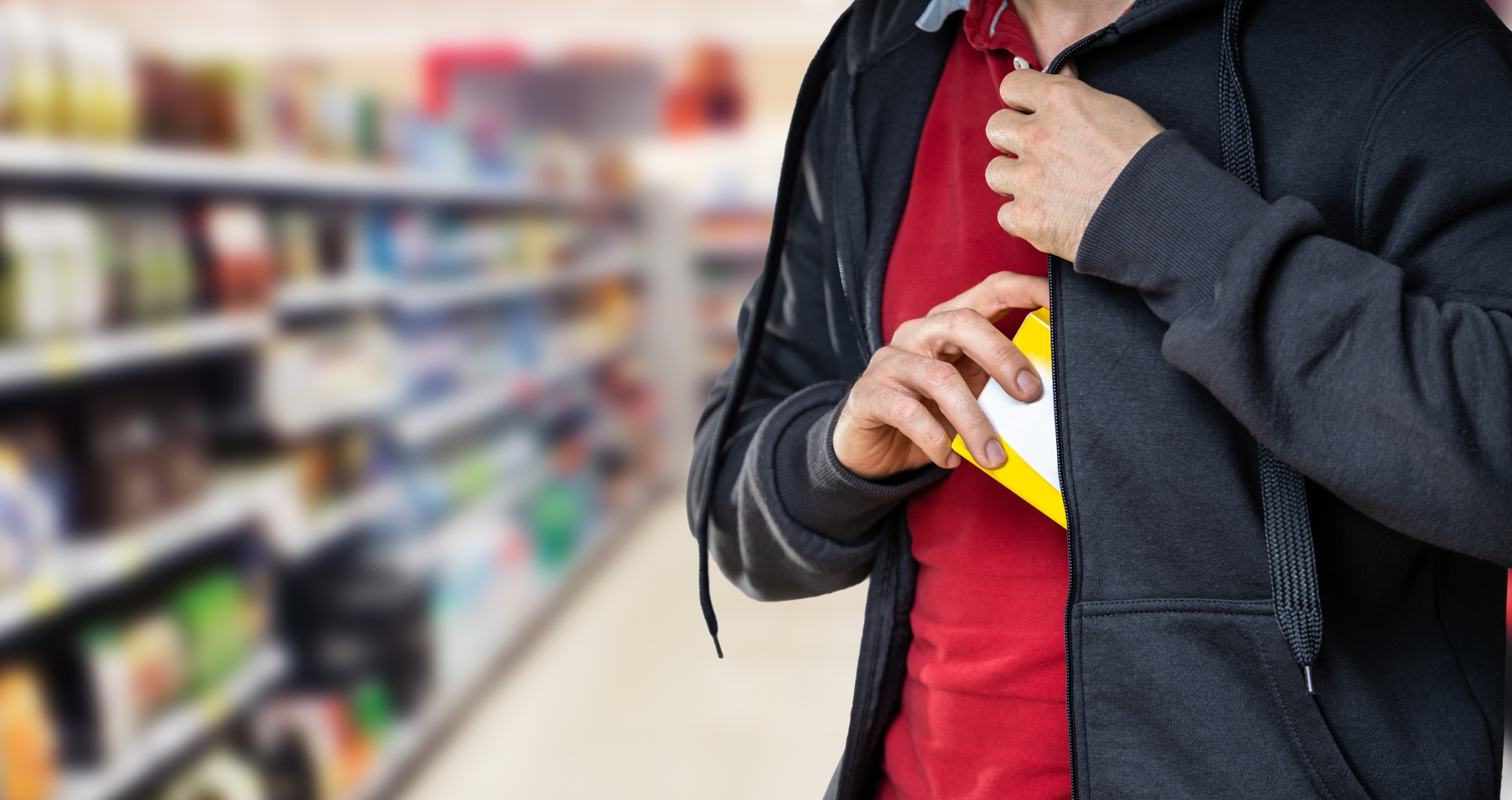 Image of a man stuffing something in his jacket at a store