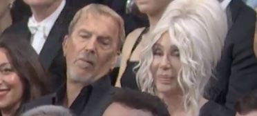 Kevin Costner grimaces siting next to share at Ryan Reynold's joke about Justin Baldoni on SNL 50 Anniversary 
