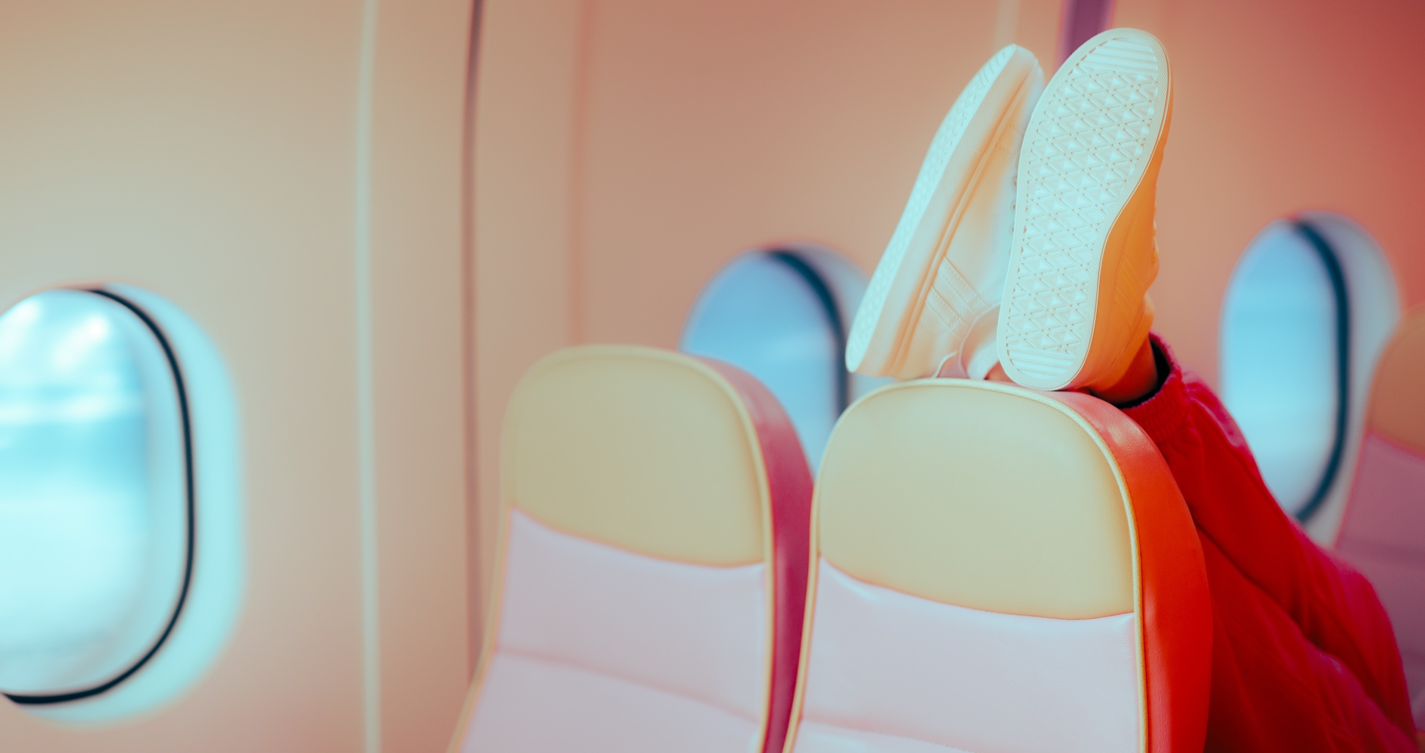 Photo of a man with his feet up on someone else's seat on a plane