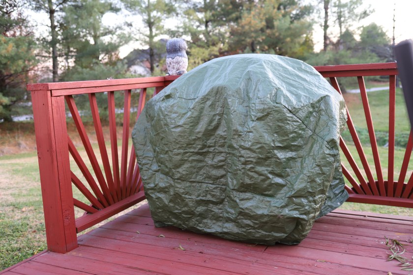 A gas grill covered with a waterproof gas grill cover in autumn