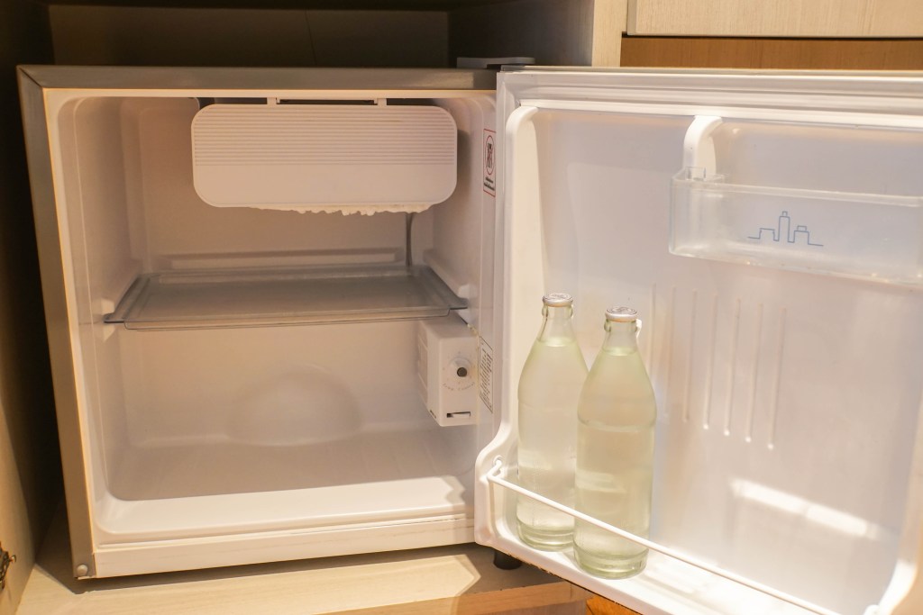 inside the mini fridge in hotel bedroom with fresh water bottle