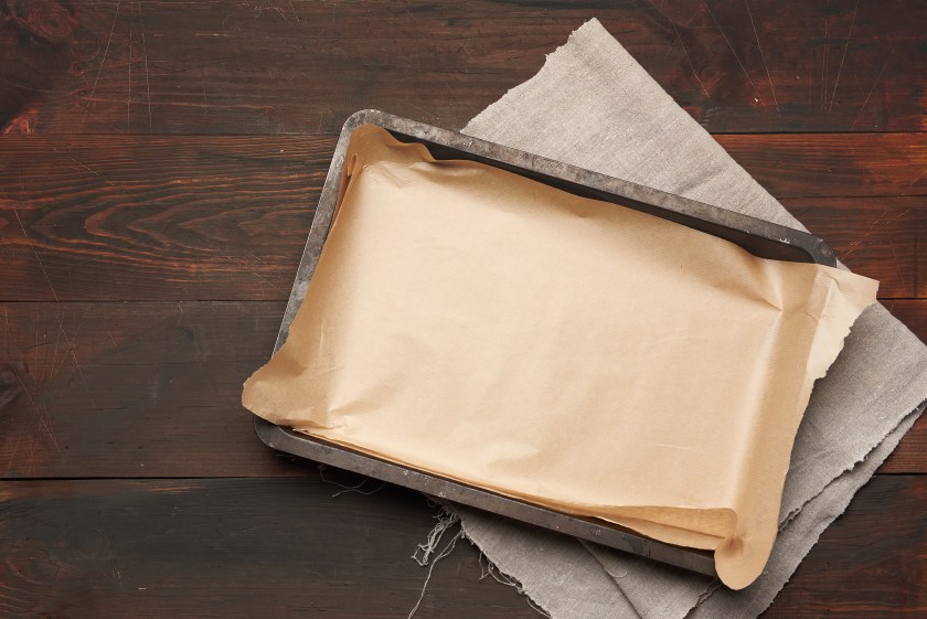 empty rectangular metal pan covered with brown parchment paper on a wooden table