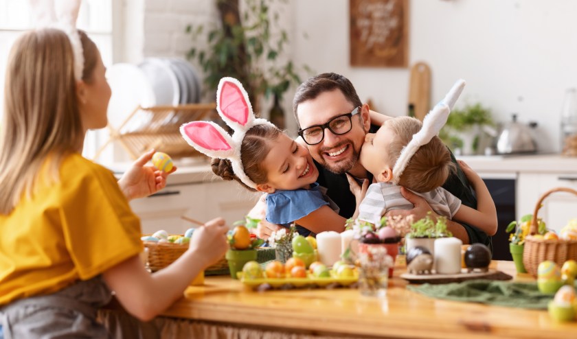 Happy children hugging and kissing father in kitchen