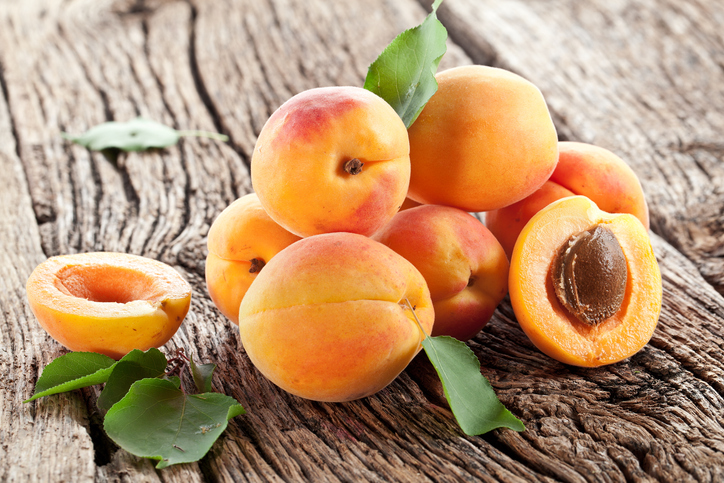 Apricots with leaves on the old wooden table.
