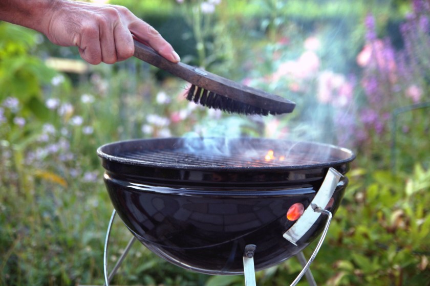 Cleaning a grill. Male hand cleans round grill with stiff brush. preparation of a grill before cooking.