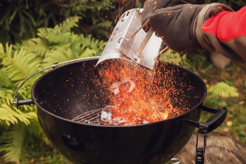 Close up man with gloves chimney starter barbecue grill in open air