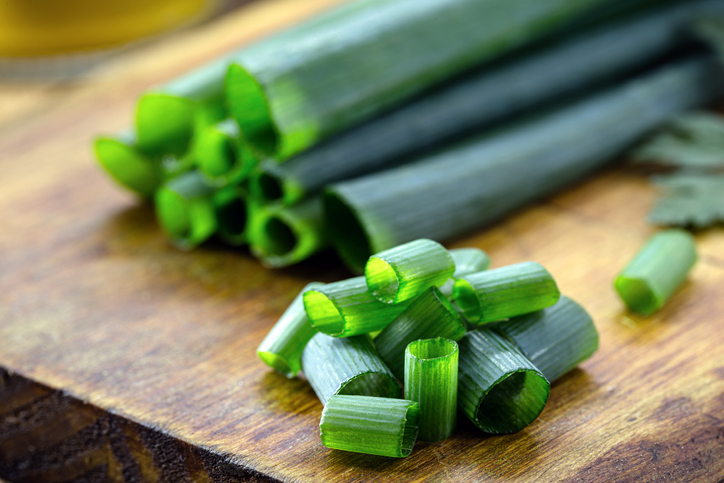 chopped green onions on wooden kitchen board