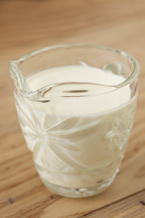 Glass jar of heavy cream on wood surface