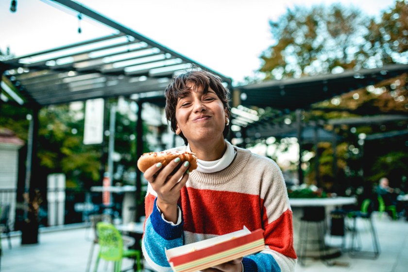 Young woman eating hot dog on the street