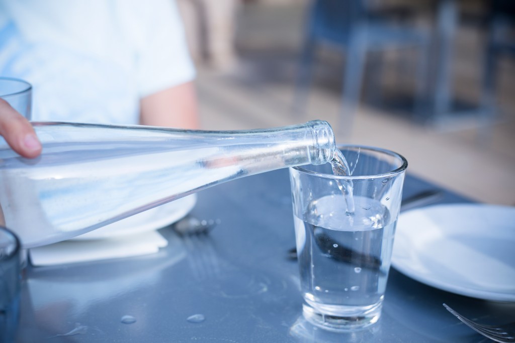Pouring Distilled water into a clear glass at a restaurant