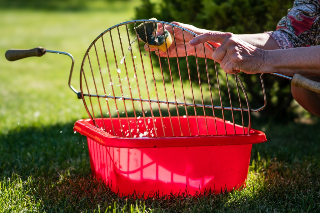 A grill is getting cleaned by a woman