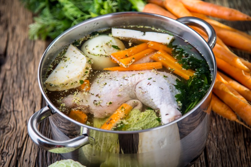 Top view of chicken soup - broth on wooden table with vegetable