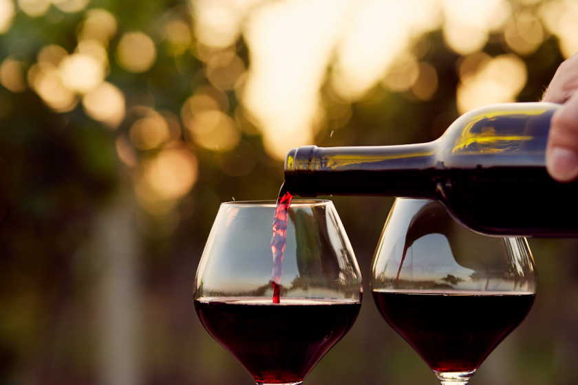 red wine glasses with wine being poured into them