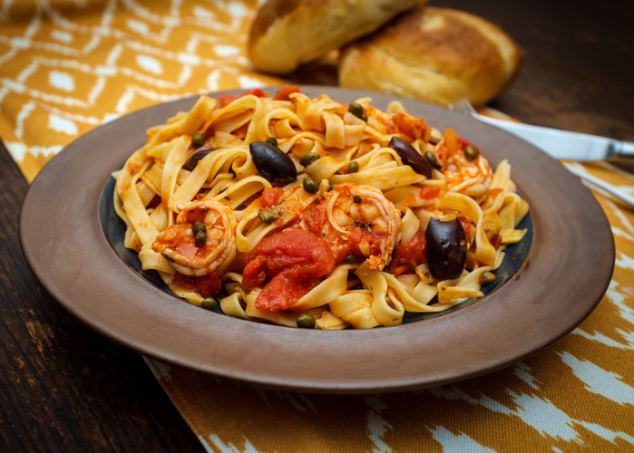 Delicious Spaghetti alla puttanesca with jumbo shrimp and fresh italian bread