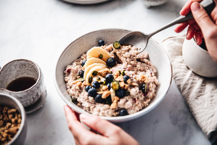 woman mixing oats flour, banana and blueberries in a bowl