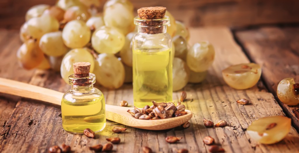 Grape seed oil in glass jar on wooden background. Selective focus